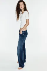 Jeans wide leg de tiro bajo y cinco bolsillos con efecto lavado y cierre frontal con cremallera y botón metálico.