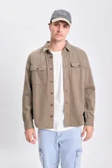 Sobrecamisa de gabardina verde militar, de corte recto, con mangas largas, bolsillos frontales con solapa y botones, y cierre frontal abotonado.