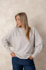 Buzo de punto color azul petróleo, con cuello redondo, mangas largas con puños ajustados y detalles de textura trenzada en la parte superior y el ruedo.