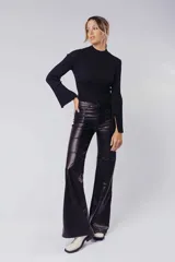 Pantalón de tiro alto confeccionado en material sintético efecto piel, con diseño de corte recto y acabado brillante. Presenta costuras verticales que definen la silueta y cierre frontal con botón y cremallera.