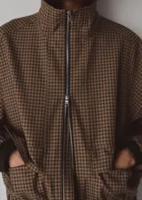 Chaqueta de diseño recto con estampado de pata de gallo, cuello alto y manga larga con puños elásticos. Cuenta con cierre delantero de cremallera y dos bolsillos con solapa en la parte delantera.