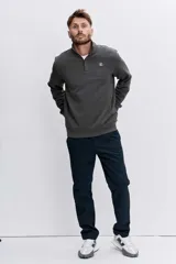 Sudadera de cuello alto con cierre frontal parcial, de manga larga y diseño liso en color gris oscuro. Presenta un pequeño logo bordado en el pecho.