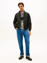 Campera tipo Harrington de Tommy Hilfiger en color negro, de corte amplio y tejido repelente al agua. Cuenta con cuello levantado, cierre frontal de cremallera con botón, bolsillos de ojal en la cintura, y puños y bajo de punto canalé. Presenta el logo de la marca bordado en el pecho.
