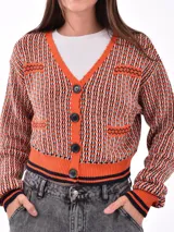 Saco tejido de punto grueso, color negro, con cuello en V y botones frontales. Presenta detalles de punto en contraste en los bolsillos y puños.