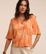 Blusa color naranja con estampado de cocoteros en blanco y rojo, cuello en V con detalle de abalorio de madera y mangas cortas acampanadas.