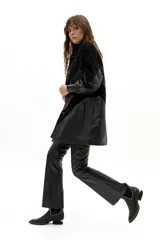 Chaqueta larga de diseño oversized confeccionada en una combinación de cuero de oveja y gamuza de cabra. Presenta cortes en forma de V, hombreras marcadas, cuello camisero redondeado, bolsillos frontales y cierre con botones a presión forrados. Incluye forro interior capitoneado y bolsillo interno.