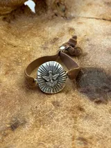 Pulsera con dije plateado con la imagen del Espíritu Santo y cinta de terciopelo elástica color verde petróleo.