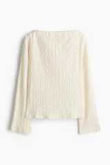 Top de manga larga color blanco roto, confeccionado en punto texturizado con escote bote y hombros levemente caídos.