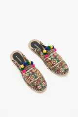 Zueco de punta cerrada con diseño multicolor, decorado con bordados étnicos, lentejuelas, canutillos y pompones de colores. Presenta una suela de yute tipo alpargata con un pequeño taco de madera de 1,5 cm y forro de cuero caprino.