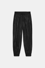 Pantalón negro de tiro medio con acabado brillante, cintura elástica ajustable con cordones y puños elásticos en los tobillos.