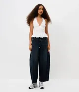 Pantalón de jean corte barrel con cintura media, trabillas para cinturón, bolsillos delanteros y traseros, cierre tradicional y detalle de recorte transversal en los laterales.