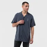 Camisa de manga corta en color gris oscuro, confeccionada en viscosa con cuello tipo cubano y cierre frontal de botones. Presenta un pequeño estampado circular en el pecho con la inscripción Black.