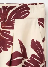 Pantalón de corte regular y tiro medio, con diseño fluido y estampado floral en color bordó sobre fondo beige.