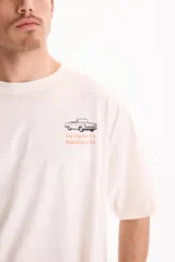 Remera oversize de manga corta color blanco, confeccionada en 100% algodón, con estampado gráfico en la espalda que incluye el texto "Los Angeles, PARADISE CITY" y un dibujo de un auto clásico.