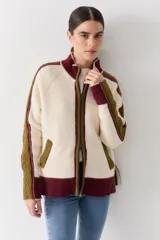 Campera de tejido de punto con cierre frontal, cuello alto y diseño color block en tonos marrón, rosa y rojo. Presenta detalles de trenzas en las mangas y puños y ruedo acanalados.