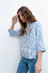 Camisa de mangas 3/4 con estampado abstracto en tonos azules y blancos, con cuello clásico y cierre frontal con botones.