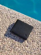 Billetera de cuero negra con logo en la esquina inferior derecha.