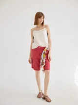 Short de lino color rojo, de tiro medio, con cierre frontal y bolsillos laterales. Presenta un diseño clásico y versátil.