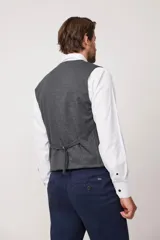 Chaleco azul con textura de espiga, cuello en V, cierre abotonado y bolsillos delanteros.