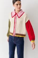 Cardigan de punto con diseño color block, cuello estilo polo en color rosado con borde rojo, cierre frontal con botones, manga derecha en verde oliva y manga izquierda en rojo, con puños y ruedo acanalados a rayas multicolor.