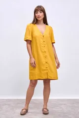 Vestido corto color mostaza de lino, con escote en V, mangas cortas abullonadas y cierre frontal con botones.