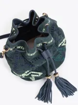Bandolera tipo bucket bag confeccionada en gamuza color verde oscuro con bordados decorativos en hilo claro. Presenta cierre de cordón ajustable con borlas en los extremos, correa larga regulable de cuero y detalles metálicos dorados.