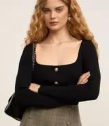 Blusa cropped de punto negra con escote cuadrado, manga larga y botones dorados.