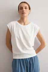 Remera mostaza de manga corta con detalles de encaje bordado (broderie) en los hombros, cuello redondo y corte recto.