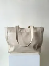 Cartera tipo shopper de cuero marrón texturado, con doble asa de hombro y un bolsillo frontal amplio con cierre de imán.
