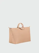Bolso de viaje grande tipo tote de la línea Le Pliage One de Longchamp, en color beige. Presenta un diseño minimalista con cierre superior, doble asa corta y solapa frontal con botón a presión.