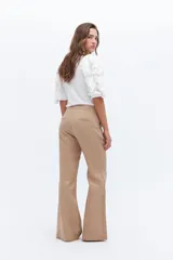 Remera color beige con mangas cortas y volados con borde naranja.