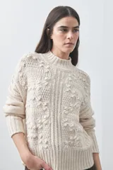 Polera de tejido de punto color marrón, con cuello alto y diseño de textura con relieves y trenzas. Posee mangas largas con puños acanalados.
