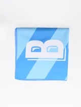 Toalla de playa de microfibra celeste con diseño de bloques de color y una letra B blanca en el centro.