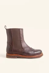 Bota tipo Chelsea de cuero vacuno color marrón, con detalles de perforaciones estilo brogue en la puntera y laterales. Cuenta con paneles elásticos laterales, tirador trasero y suela de goma con plataforma.