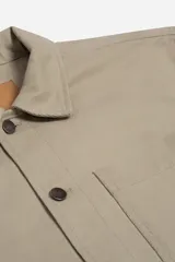 Sobrecamisa de tejido twill de algodón en color beige, con estructura firme, cuello clásico, cierre frontal con botones metálicos y bolsillo aplicado en el pecho.