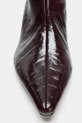 Bota de caña alta con acabado efecto craquelado en color marrón oscuro. Presenta un diseño de punta fina, tacón kitten y una estructura de calce fácil tipo pull-on.