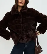 Campera de pelo artificial color marrón oscuro, con diseño de gajos horizontales, manga larga y cuello alto estructurado.