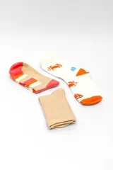 Pack de tres pares de medias estilo crew con diseños variados: un par liso en color tostado, un par beige con rayas horizontales en tonos terracota y blanco, y un par blanco con estampado de cangrejos y veleros naranjas.