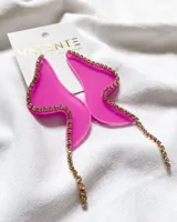 Par de aros colgantes con forma irregular, confeccionados en acrílico fucsia y bordeados con strass dorado.