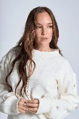 Sweater color crema de hilado frizado con cuello redondo y mangas largas. Presenta apliques de flores en los hombros y mangas.