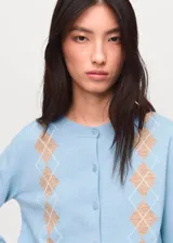 Cardigan de punto fino en color celeste con diseño de rombos en tonos beige. Presenta cuello redondo, cierre frontal con botones y mangas largas.