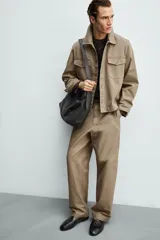 Sobrecamisa de corte boxy fit confeccionada en algodón con estructura canvas y efecto lavado. Presenta cuello solapa, cierre frontal con botones, mangas largas con puños abotonados y bolsillos de plastrón con solapa en el pecho. Incluye detalles bordados a tono en las mangas.