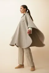 Poncho de lana fina sin teñir, con cuello camisero, cartera con broches a presión y bolsillo ojal. Diseño de estilo campestre con textura tejida.