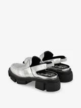 Mocasín mule de cuero negro con hebilla metálica y suela track.