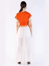 Remera color naranja de manga corta, confeccionada en algodón, con detalles de flecos y bordado en las mangas.