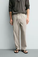 Pantalón de corte regular fit confeccionado en tejido mezcla de algodón, con cintura elástica ajustable mediante cordón, bolsillos laterales y bolsillos traseros de vivo.