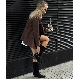 Bota alta de cuero color negro, de punta fina con puntera metálica, taco de madera y caña con flecos y detalle de hebilla con estribo desmontable.