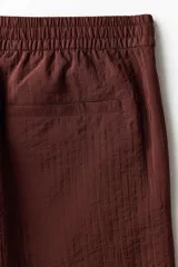 Short de corte relaxed fit confeccionado en suave tejido texturizado de mezcla de viscosa, en color bordó. Cuenta con cintura elástica con cordón ajustable, bolsillos laterales discretos y un bolsillo trasero ojal.