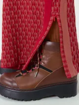 Pantalón de punto jacquard con diseño geométrico texturizado, de corte holgado y pierna ancha. Presenta tiro medio, cintura elástica con cordón ajustable y aberturas laterales en el ruedo.