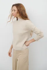 Polera de tejido de punto fino en color beige, con cuello alto y mangas largas con puños acanalados.